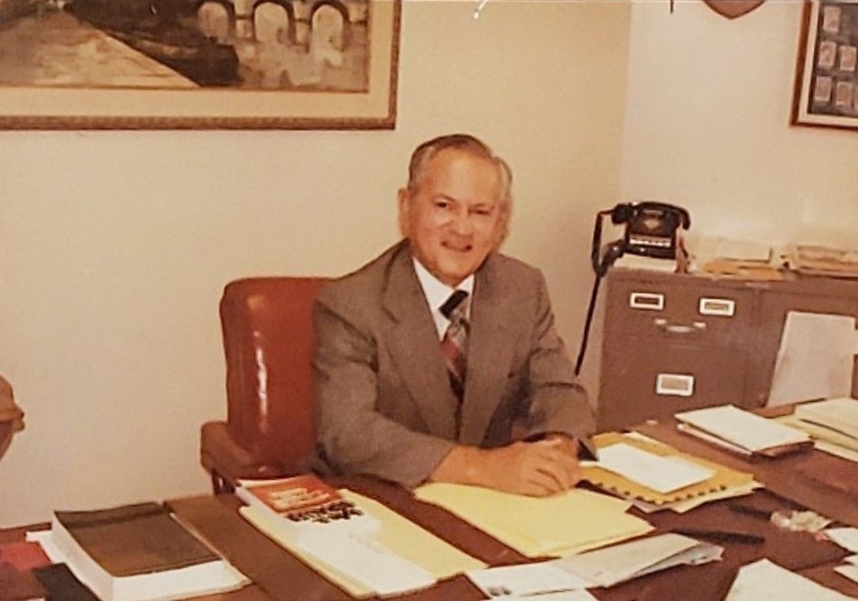 A man in a suit and tie is sitting at a desk