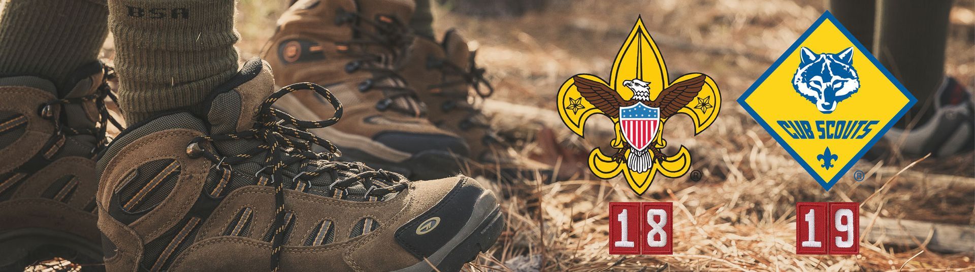 A close up of a pair of hiking boots with a boy scout badge in the background.