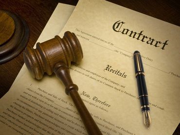 Mazo de madera, documento de contrato y bolígrafo sobre una superficie de madera.