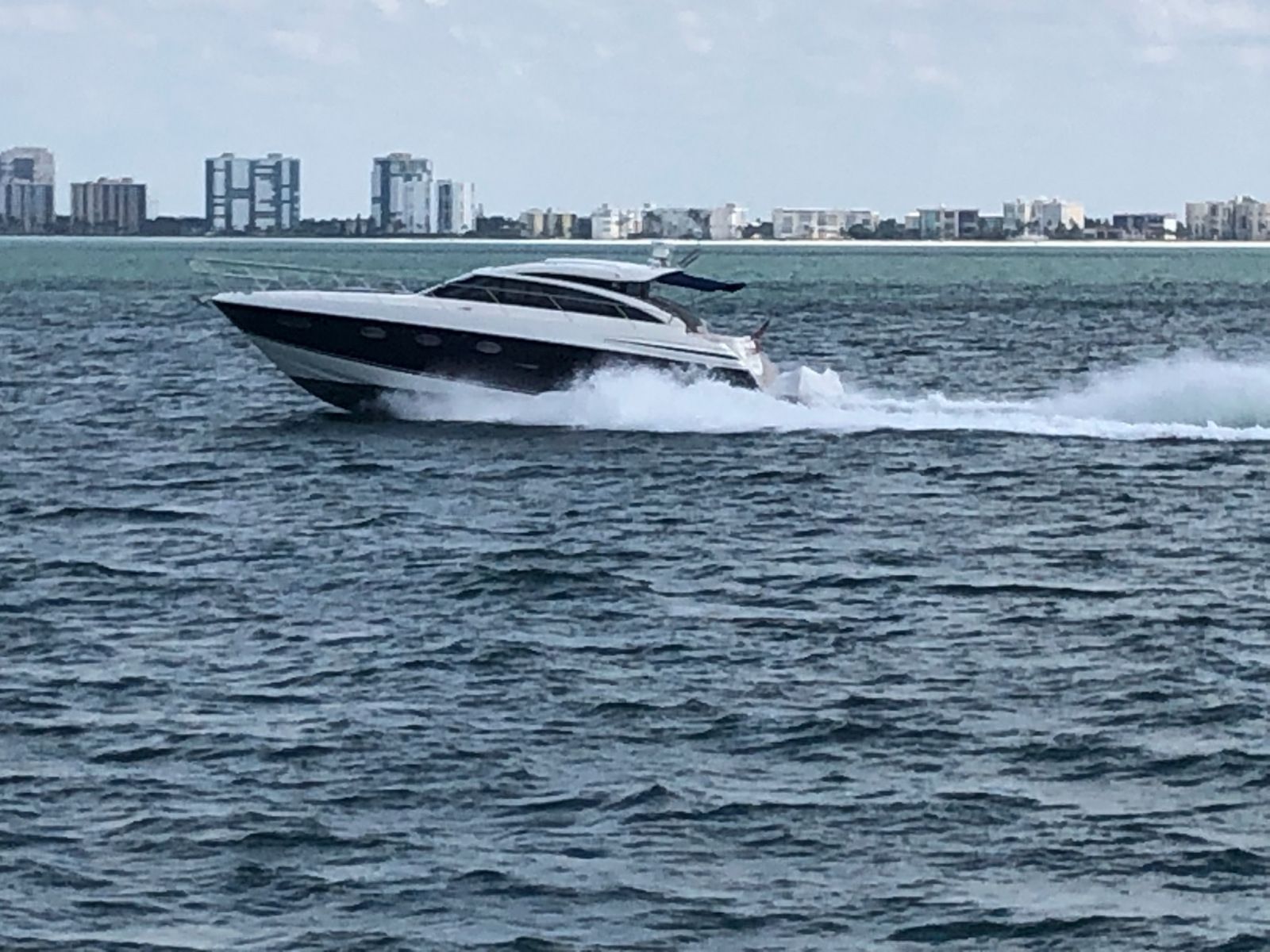 A speedboat cutting across the water, creating a wake. City buildings in the background.
