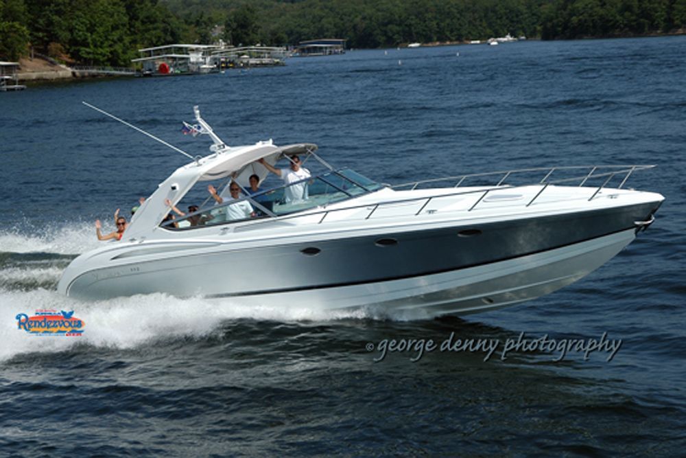 A speedboat with several people on board, cruising on a lake on a sunny day.