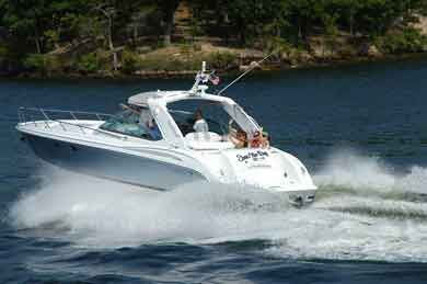 Motorboat speeding across water, white hull, people visible on board, trees in background.