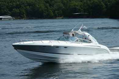 White motorboat speeding across a lake, creating a wake. Trees and water in the background.