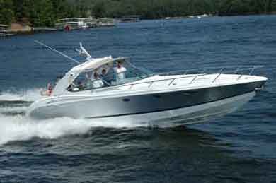 A white motorboat speeding on a lake; people on board, water and shoreline in background.
