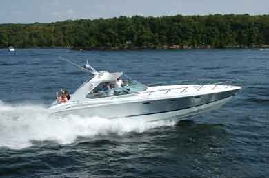 A silver motorboat speeding on a lake with trees in the background.