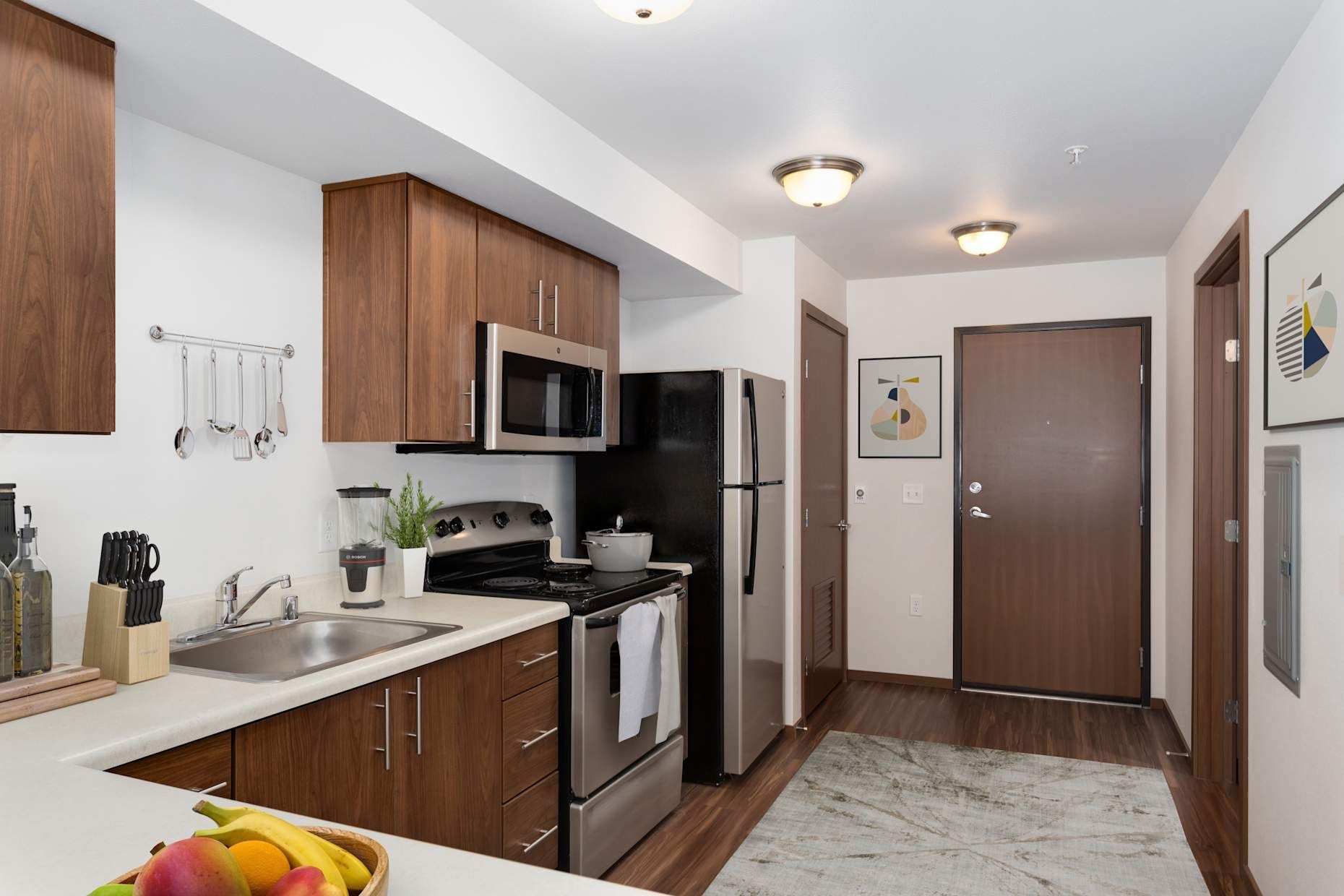 Kitchen with wood cabinets, stainless steel appliances, and a hallway with a door.