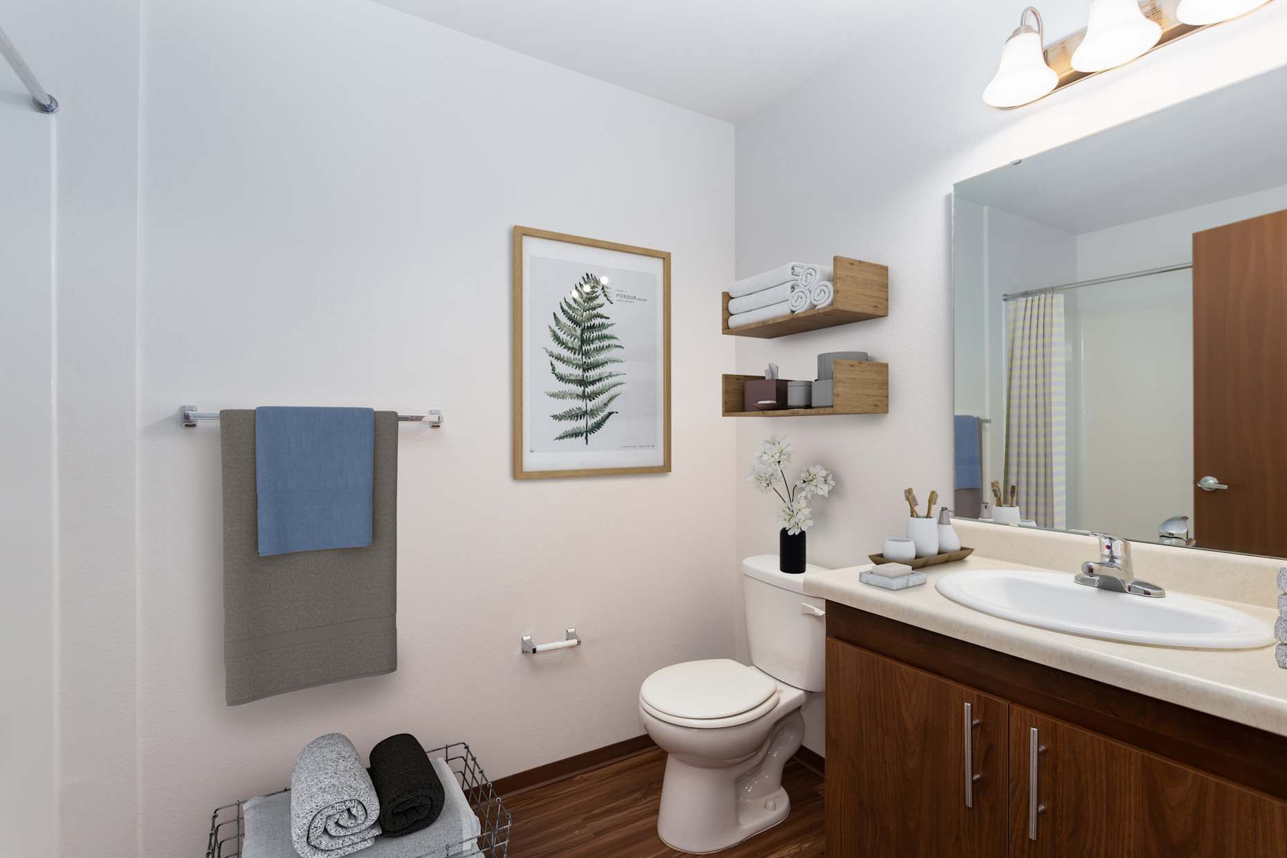 Bathroom with white walls, wood cabinet and floor, toilet, sink, artwork, and towels.