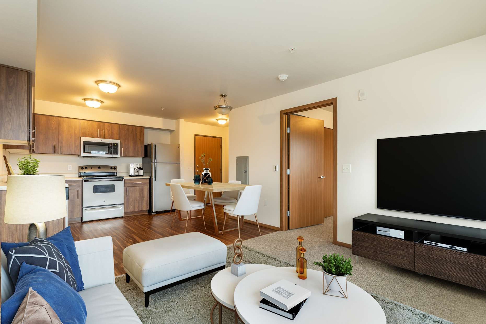 Open-concept apartment with kitchen, dining area, and living room. Modern furniture, hardwood floors, and natural light.
