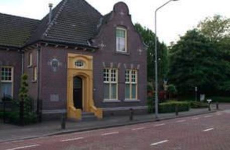 Een groot bakstenen gebouw met een gele deur staat aan de kant van de weg.