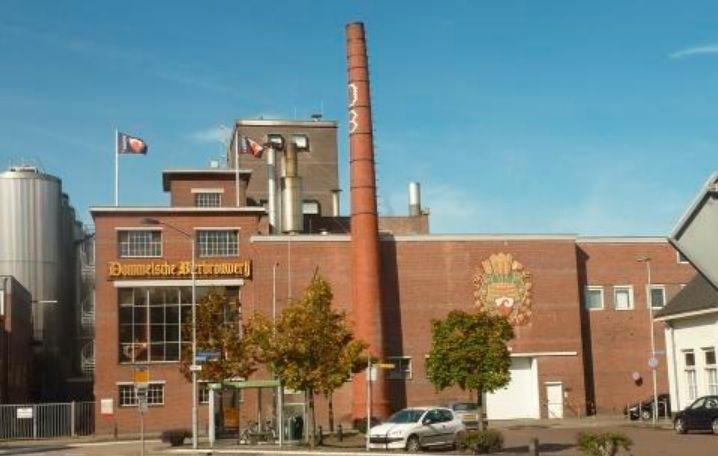 Een groot bakstenen gebouw met een schoorsteen en een bord met de tekst 'dorther brauerei' erop