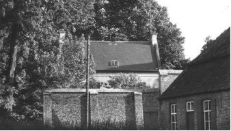 Een zwart-witfoto van een huis met bomen op de achtergrond