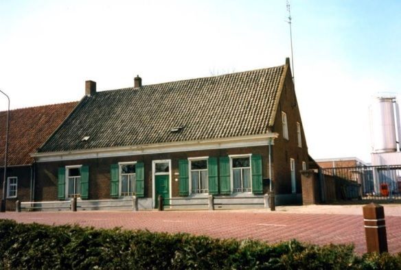 Een bakstenen huis met groene luiken voor de ramen