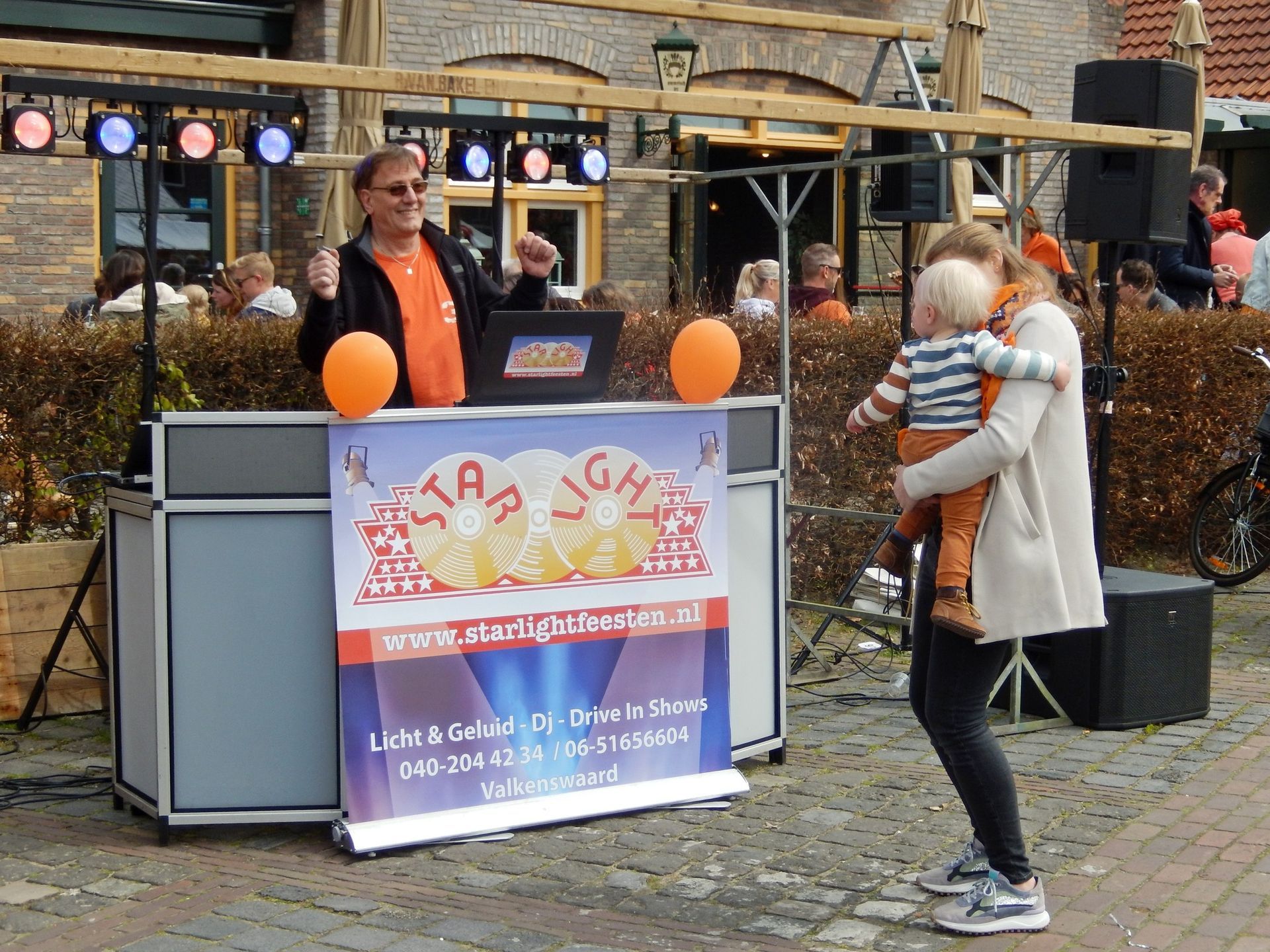 Een vrouw houdt een baby vast voor een dj-booth
