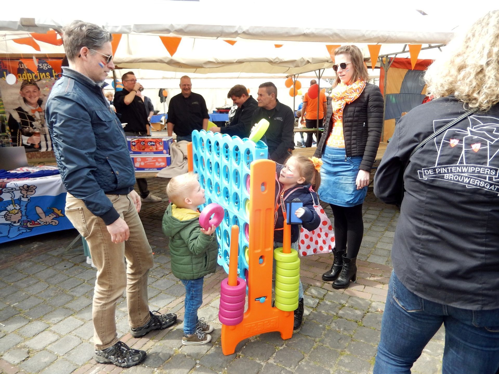 Een groep mensen speelt buiten een spelletje 'vier op een rij'.