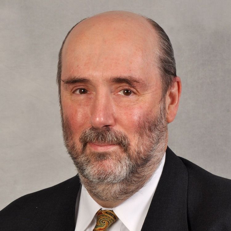 A man in a suit and tie is smiling for the camera