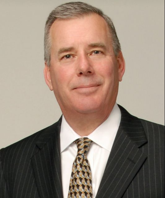 A man in a suit and tie is smiling for the camera