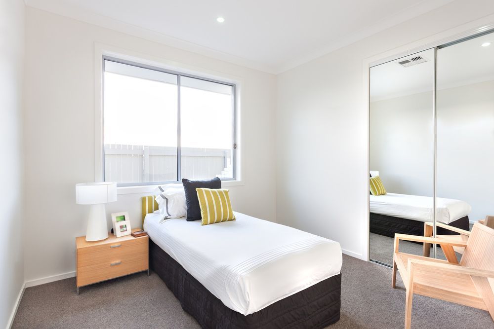 A Bedroom With A Single Bed , Nightstand , Chair And Mirrors — Morphett Construction In Gunnedah, NSW