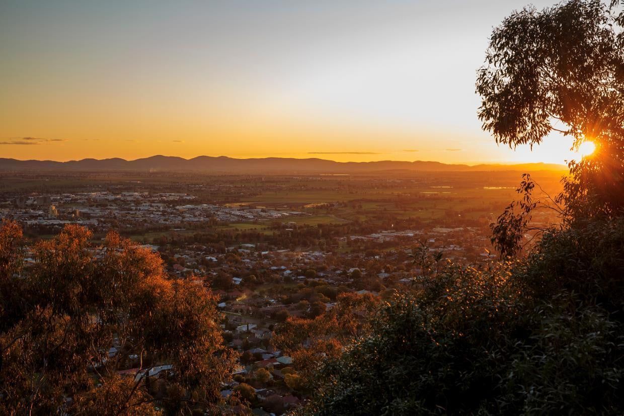 The Sun Is Setting Over A City And Mountains In The Distance — Morphett Construction In Tamworth, NSW