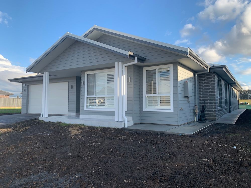A Brick House With A White Garage Door And A Blue Sky In The Background — Morphett Construction In Gunnedah, NSW