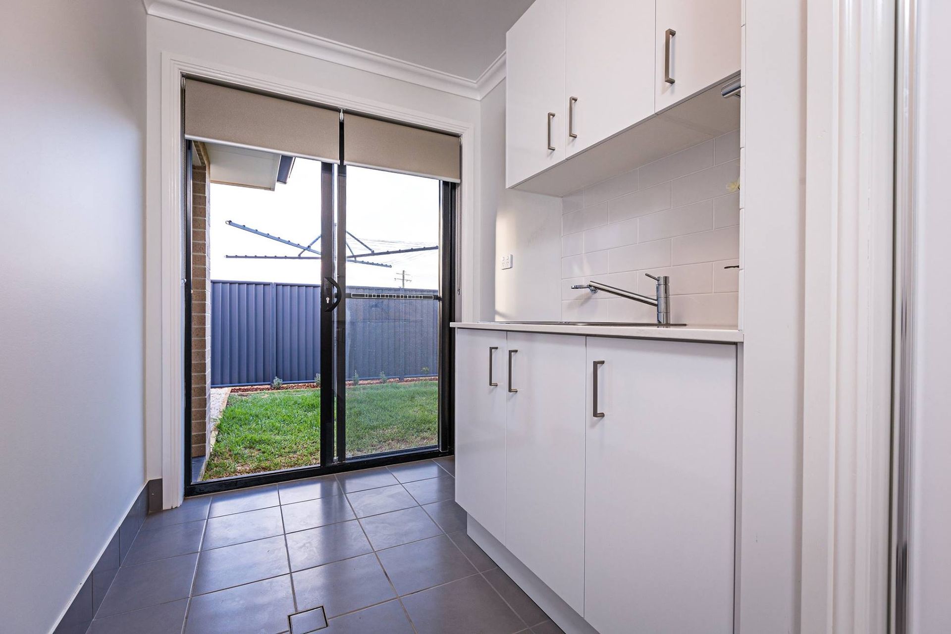 A Kitchen With White Cabinets , A Sink , And A Sliding Glass Door — Morphett Construction In Calala, NSW