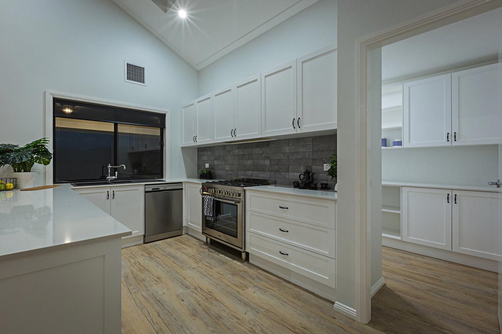 A Kitchen With White Cabinets , Stainless Steel Appliances , And Wooden Floors — Morphett Construction In Tamworth, NSW