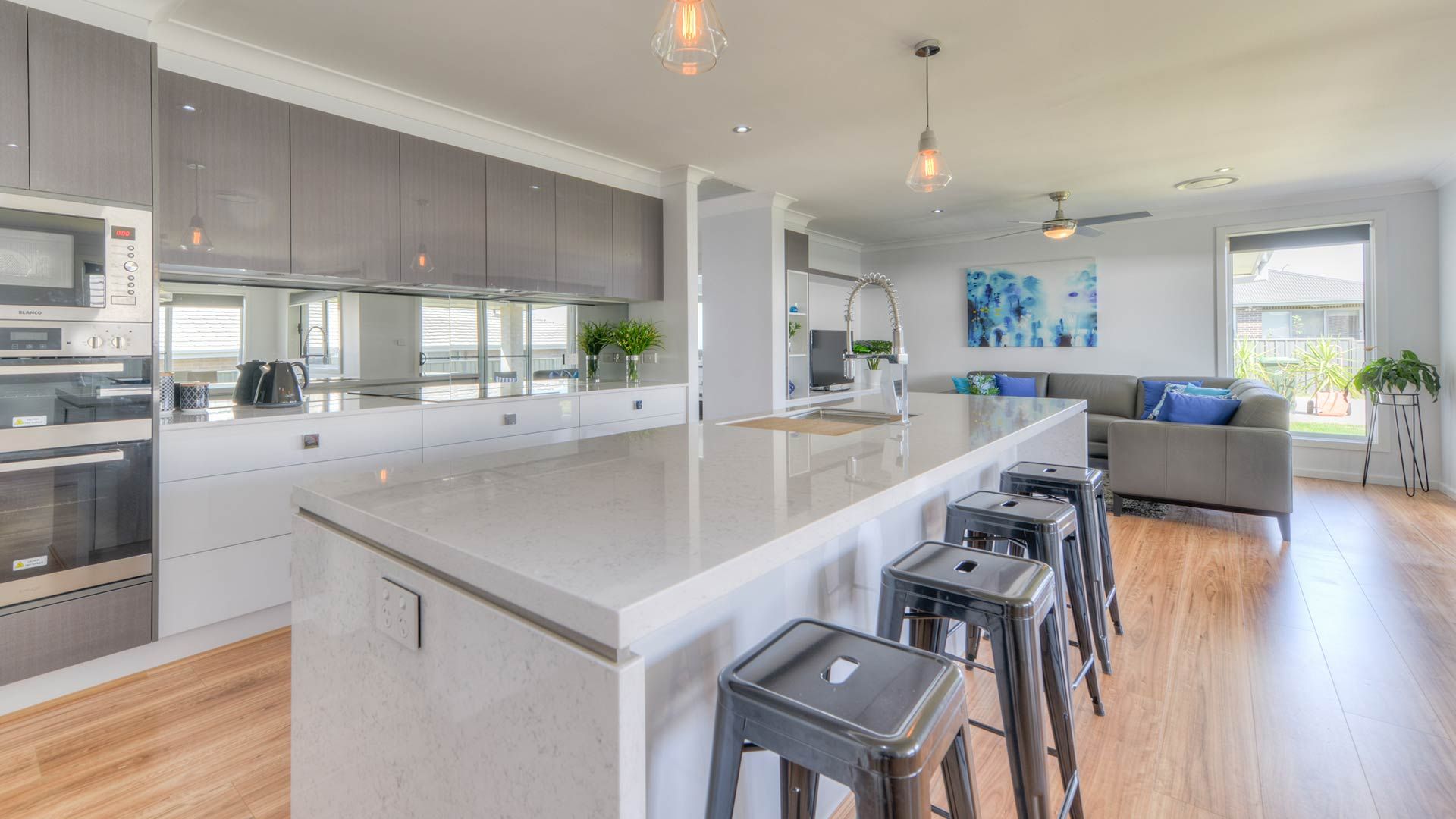 A Kitchen With A Large Island And Stools In A House — Morphett Construction In Calala, NSW