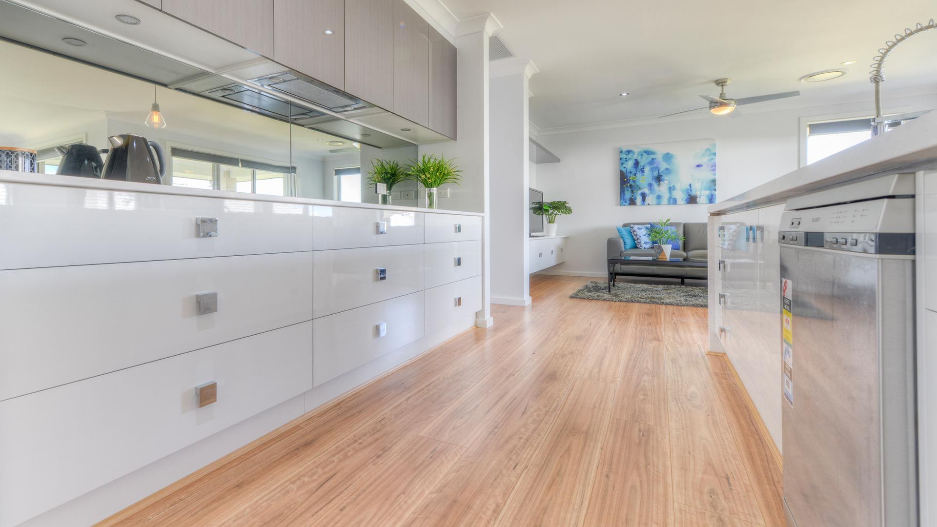 A Kitchen With Wooden Floors And White Cabinets And Stainless Steel Appliances — Morphett Construction In Calala, NSW