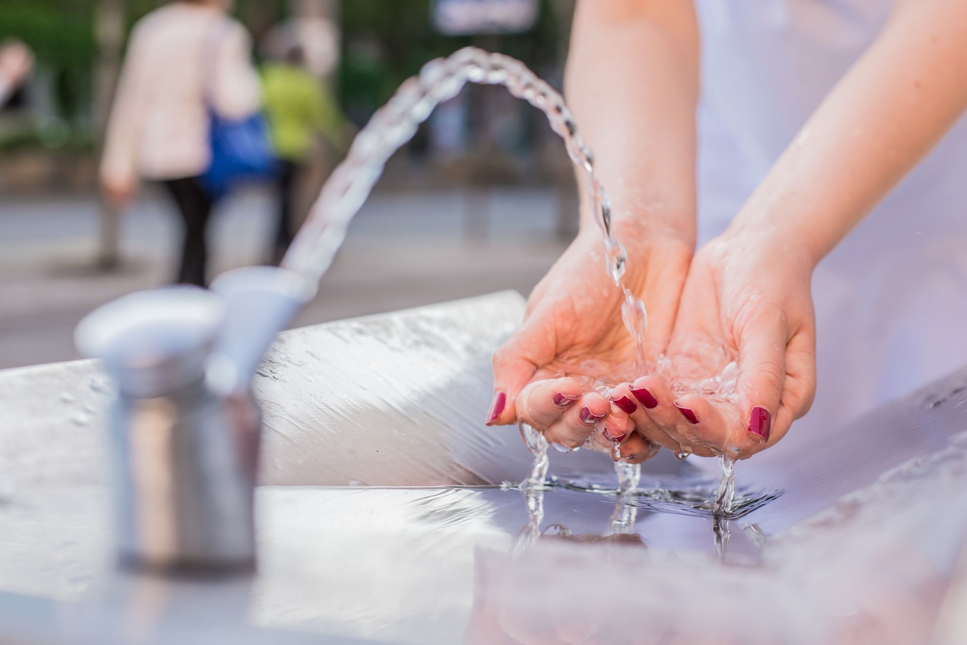 A woman is washing her hands in a fountain.