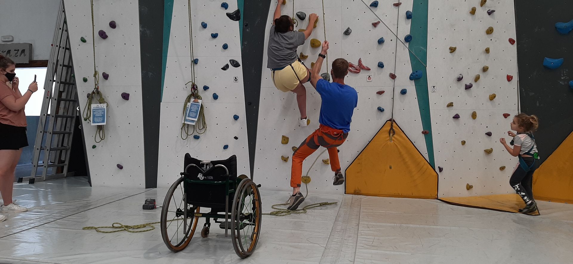 A man in a wheelchair is climbing a climbing wall.