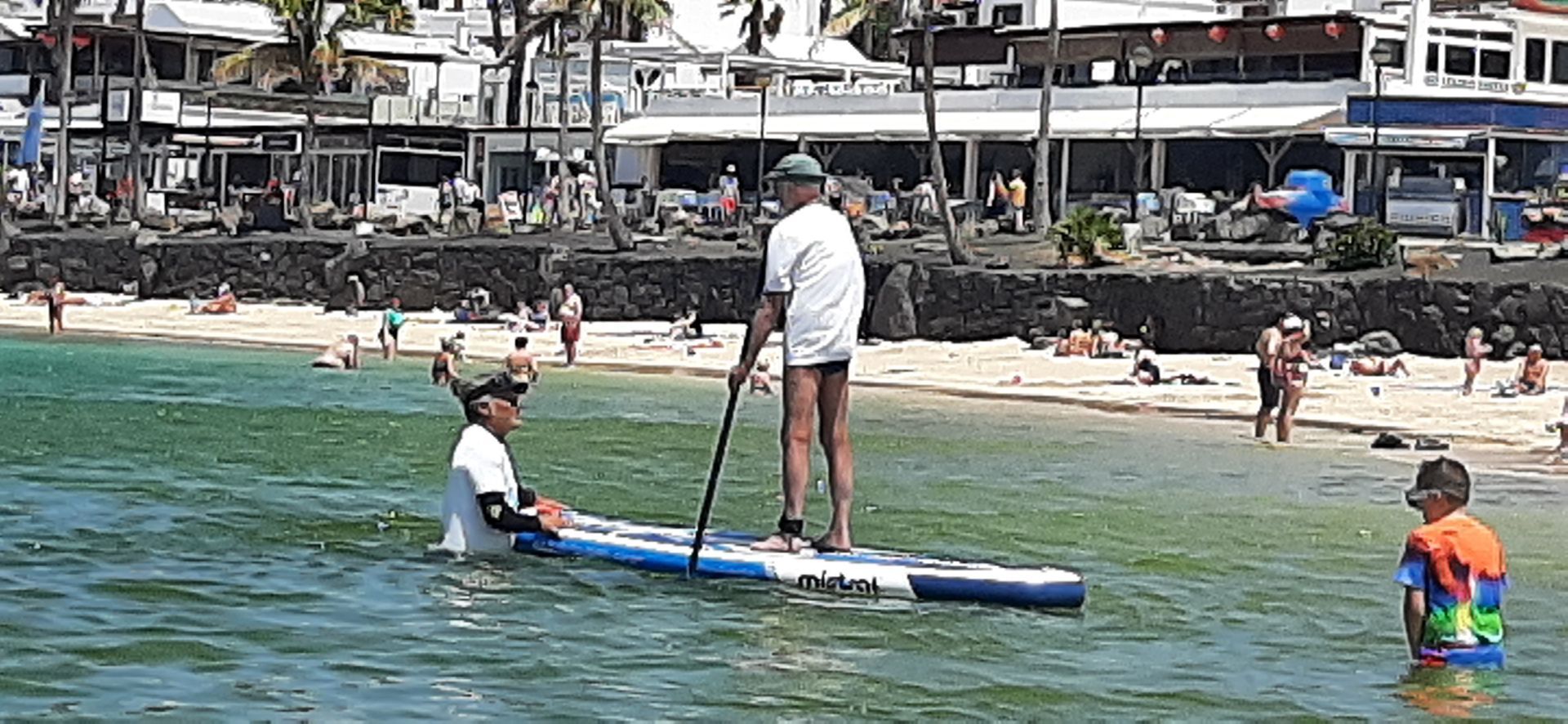 A man is standing on a paddle board in the water.