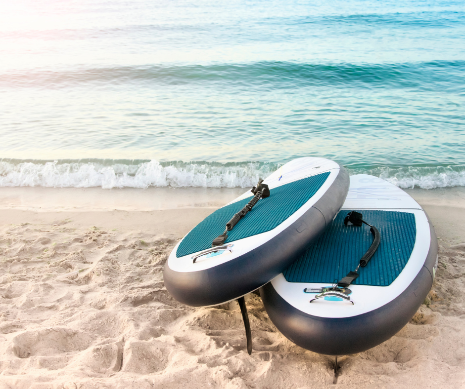 Two paddle boards are sitting on the beach near the ocean.