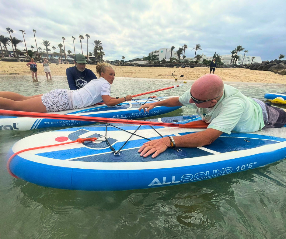 A man is laying on a paddle board in the water