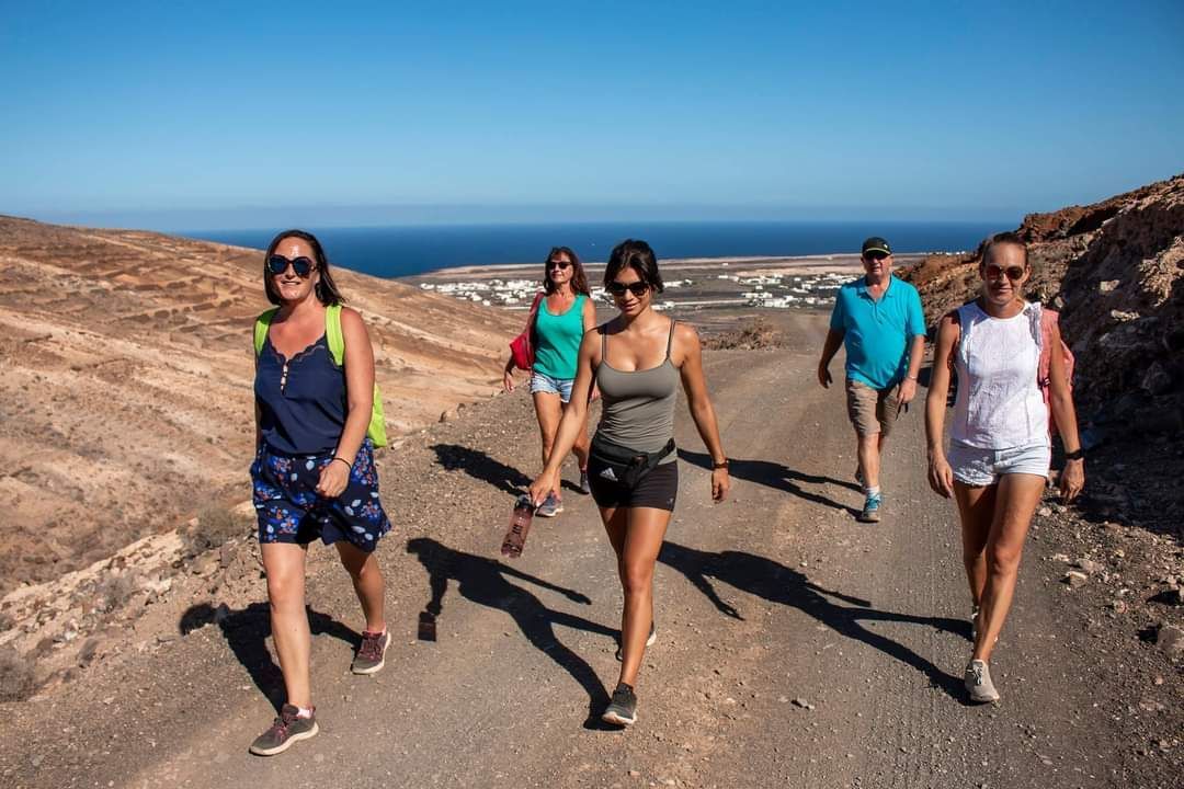 A group of people are walking down a dirt road.