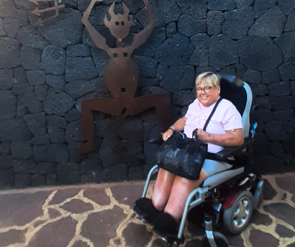 A woman in a wheelchair is sitting in front of a stone wall