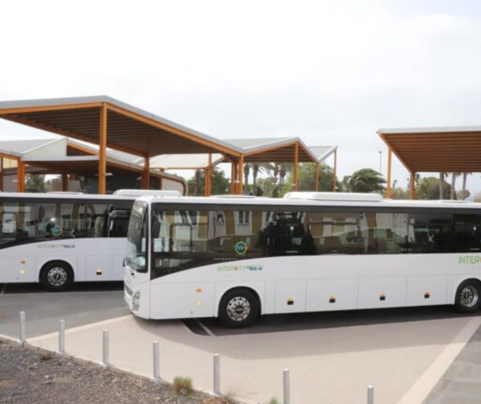 Two white buses are parked next to each other in a parking lot