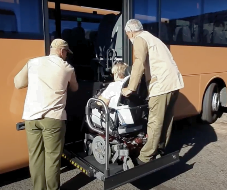 A woman in a wheelchair is getting on a bus