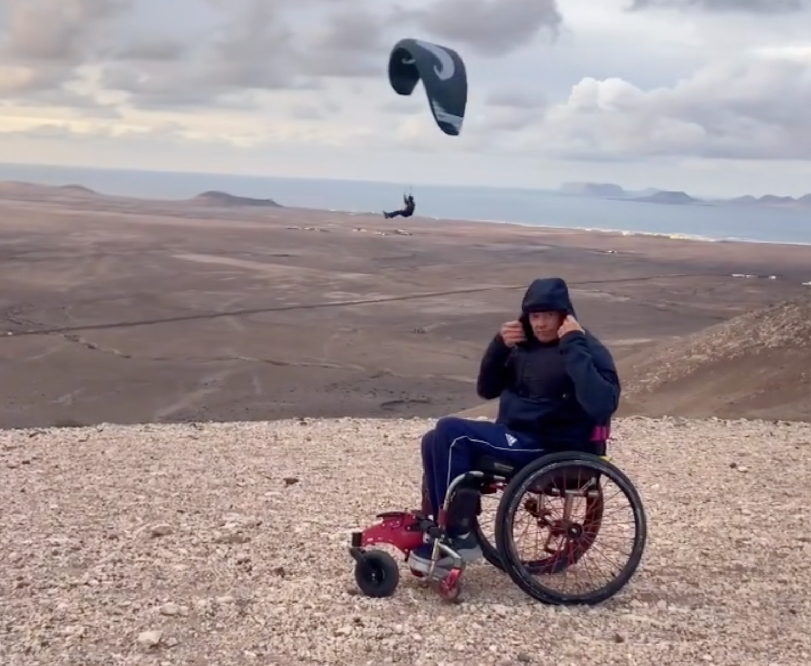 A man in a wheelchair with a parachute in the background