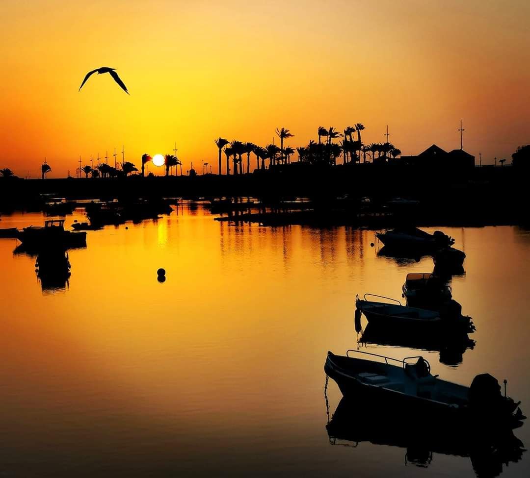 A sunset over a body of water with boats in the foreground