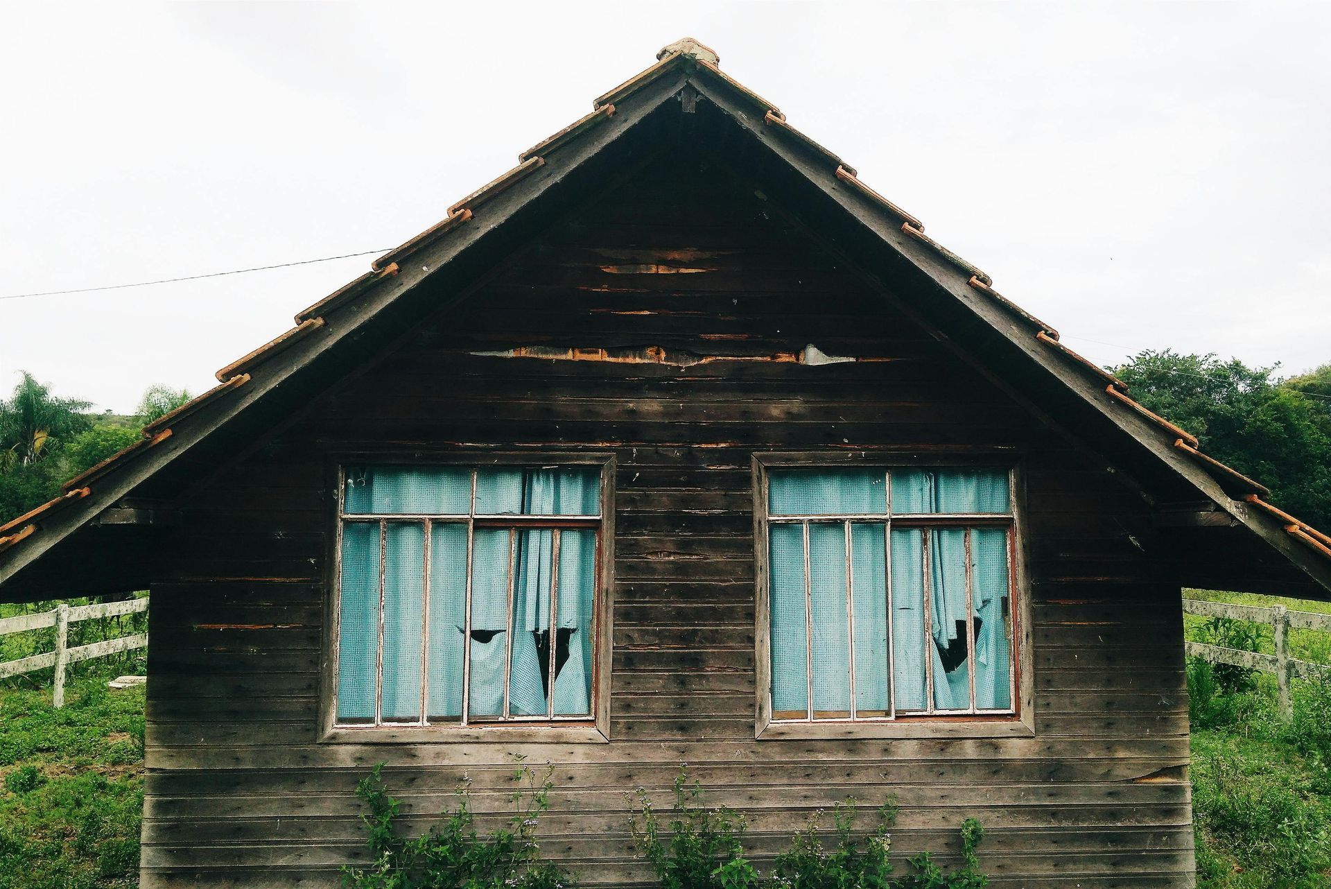 An old wooden house with blue curtains on the windows