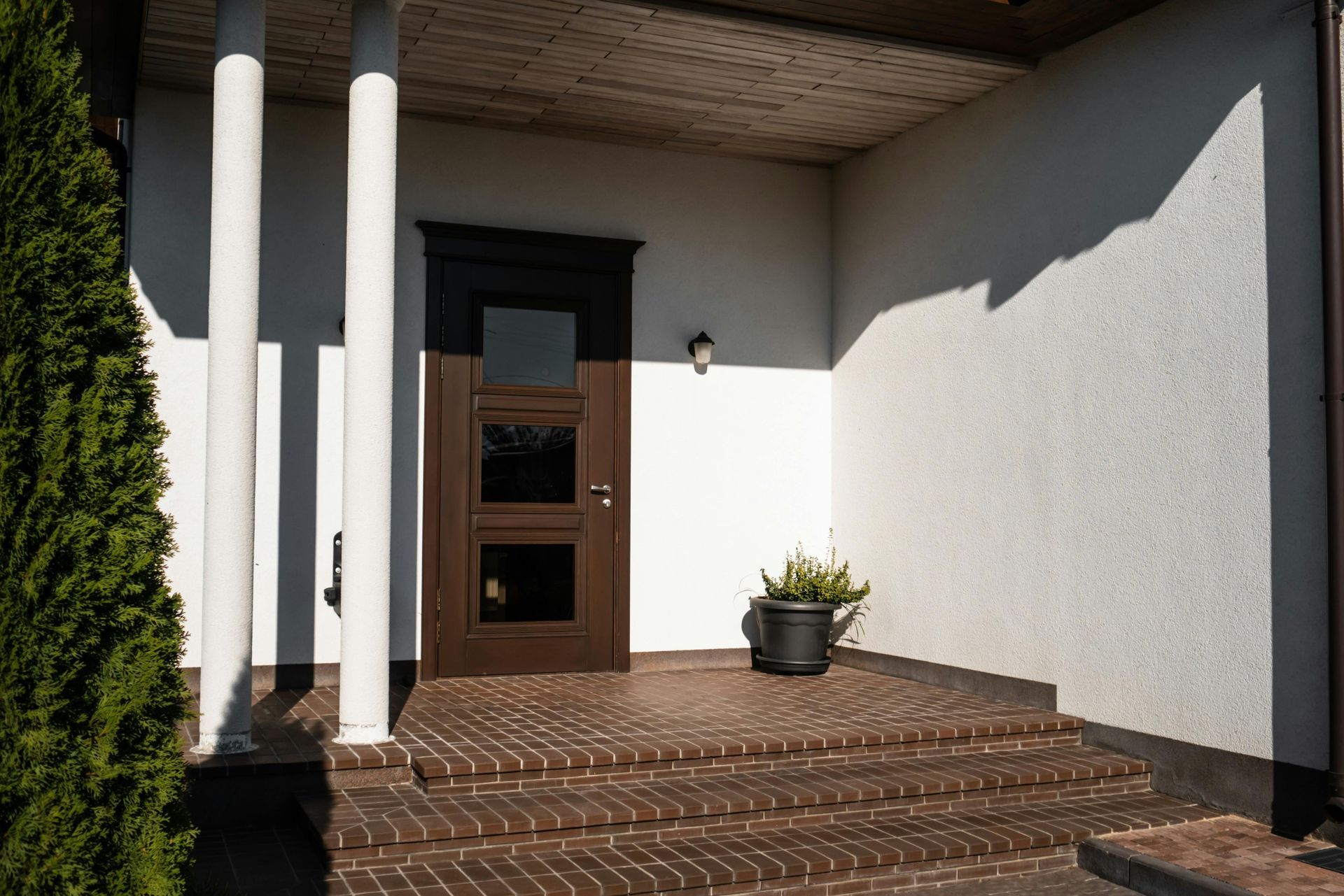 There is a potted plant on the porch of a house.