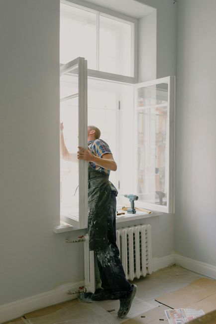 A man is installing a window in a room.
