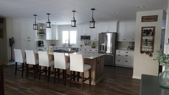 White kitchen with island seating, stainless steel appliances, and pendant lights.