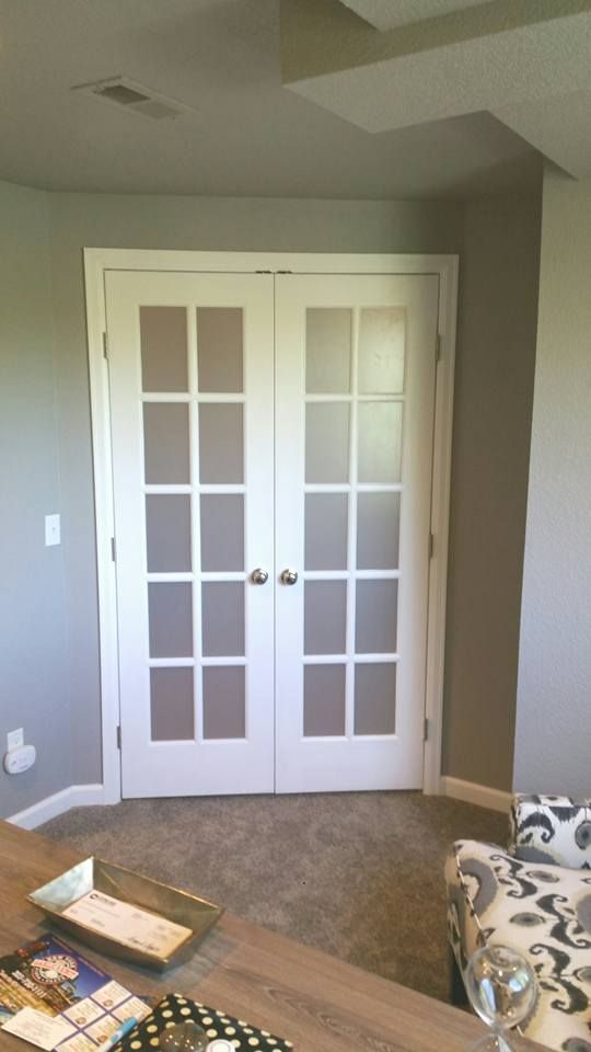 White French double doors with frosted glass panels set in a room with light grey walls and beige carpet.