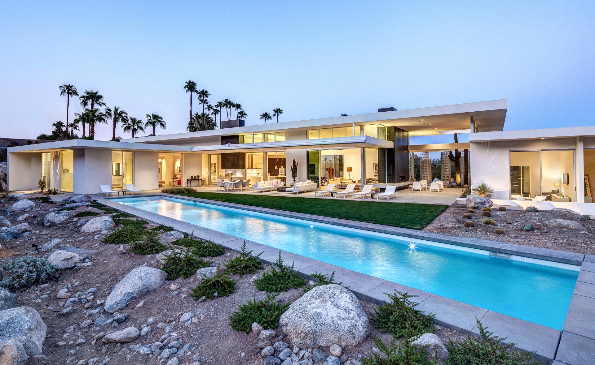 Modern home with pool and palm trees against a blue sky.