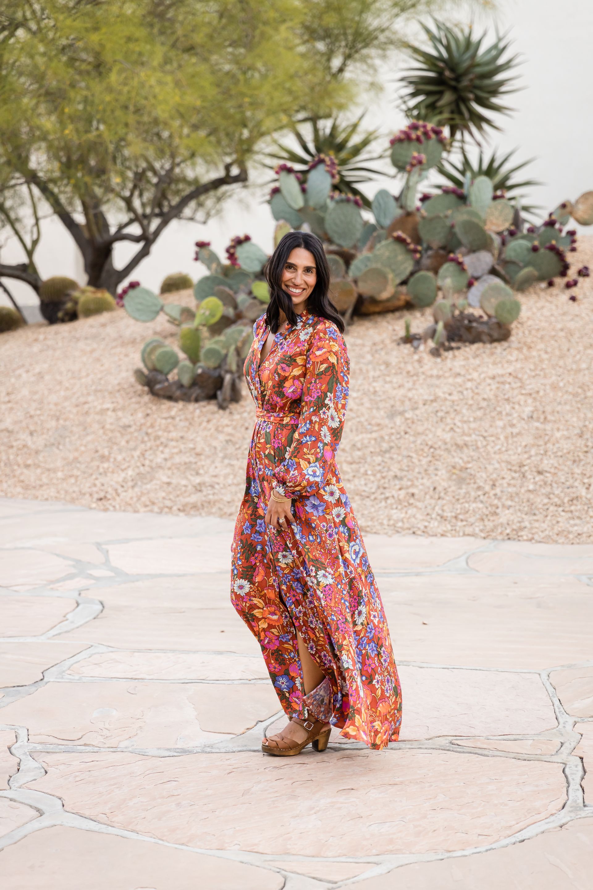 A woman in a colorful dress is smiling for the camera.
