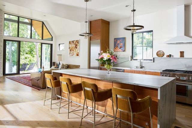 A kitchen with a large island , stools and a stove.