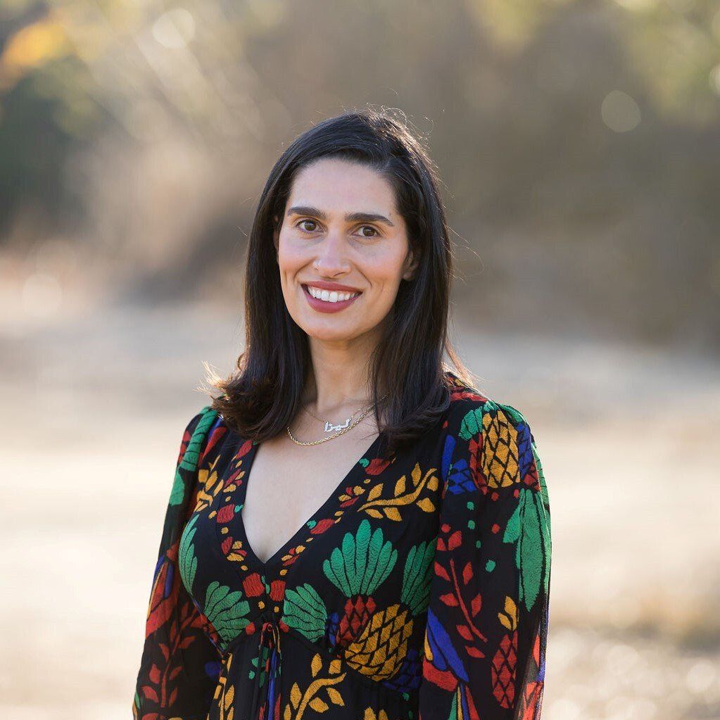 A woman in a colorful dress is smiling for the camera.