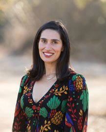 A woman in a colorful dress is smiling for the camera.