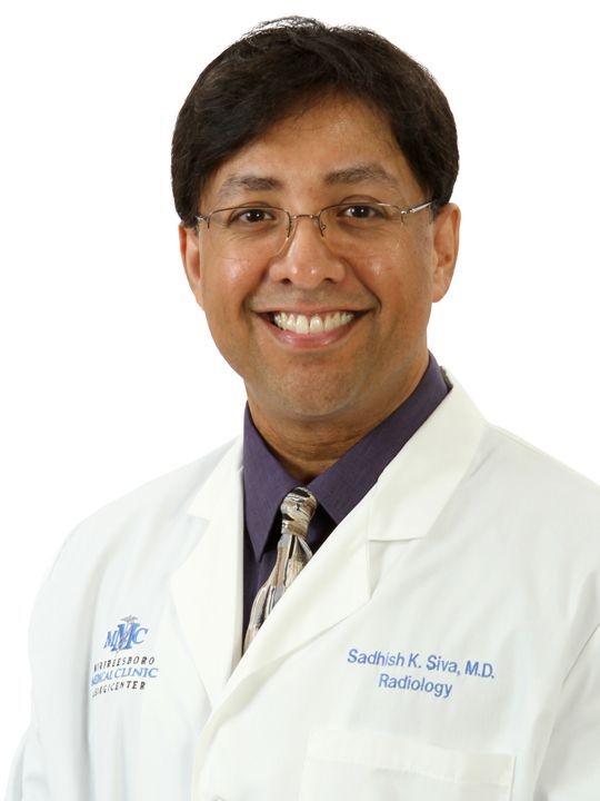 A smiling doctor wearing a white coat and tie