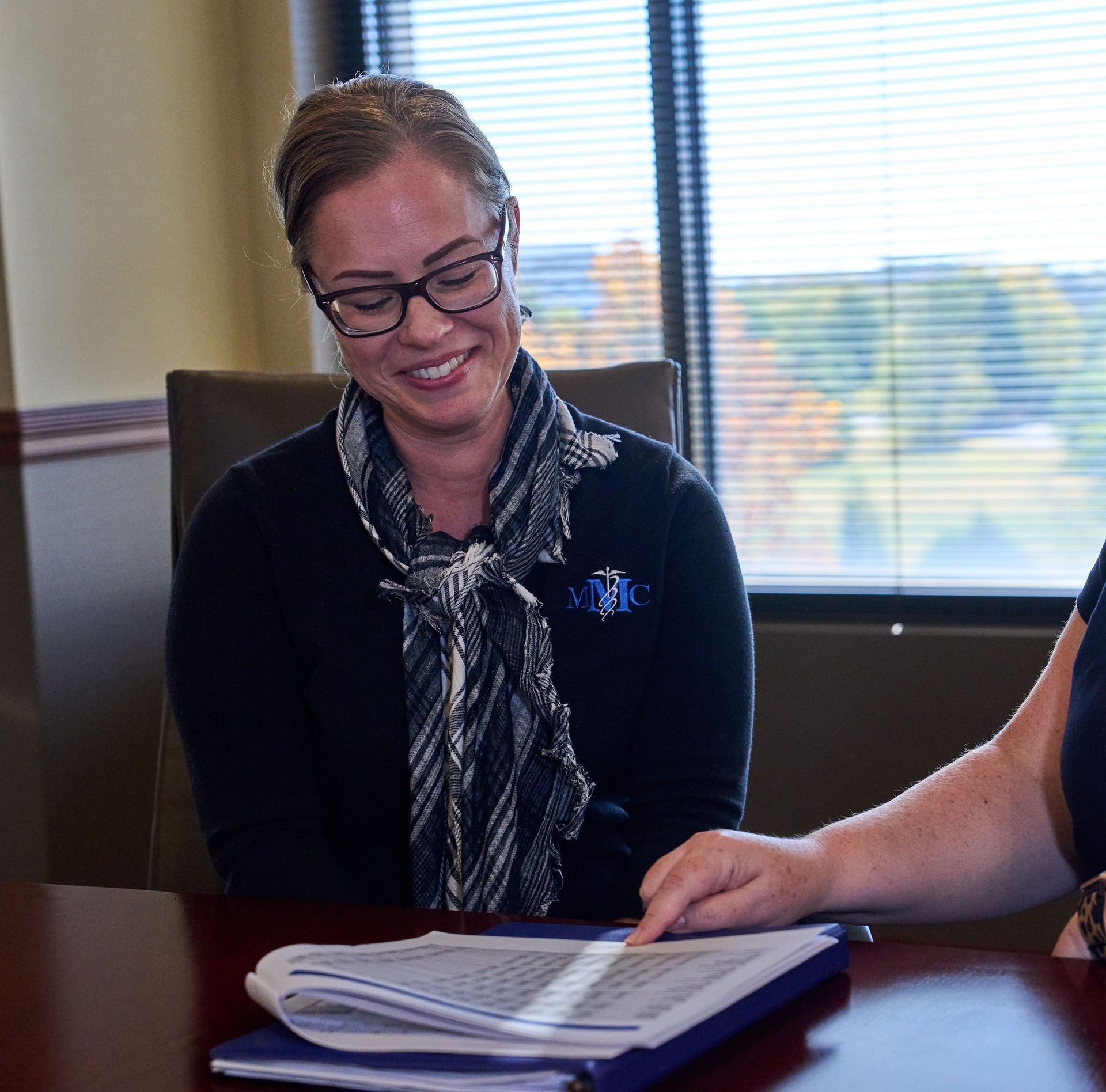 Two women are sitting at a table looking at papers.